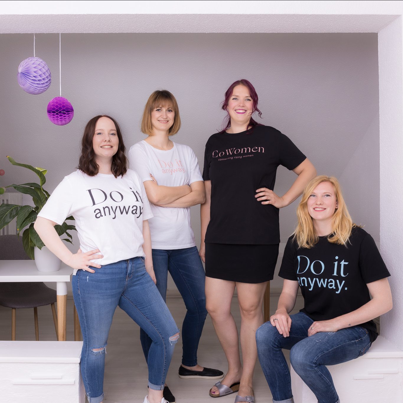 Vier Frauen stehen bzw. sitzen nebeneinander und schauen freundlich in die Kamera. Sie Tragen weiße bzw. schwarze Shirts, auf denen steht "CoWomen" bzw. "Do it anyway". (Bild: CoWomen Heidelberg / Sabine Arndt).