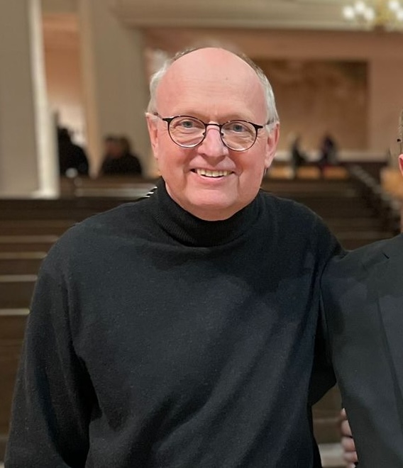 Martin Homann trägt einen schwarzen Rollkragenpullover und eine eher rundliche Brille mit schwarzem Rahmen und lächelt in die Kamera (Bild: Klangforum).