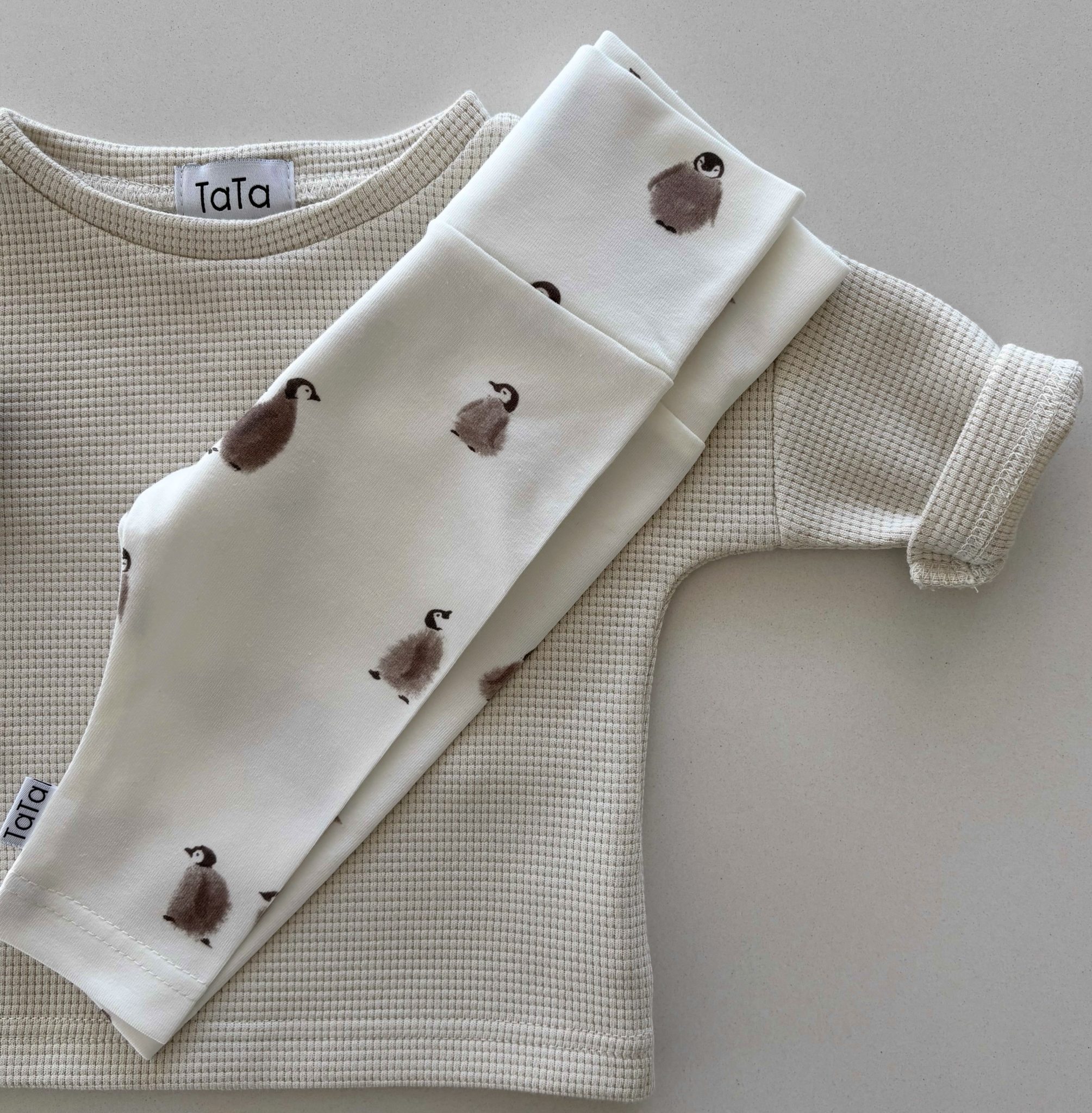 Ein Zweiteiler für Kleinkinder der Marke "TaTa" mit kleinen Pinguinen auf der Hose